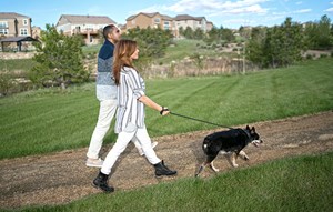 Couple walking dog on trails in Colorado master-planned community